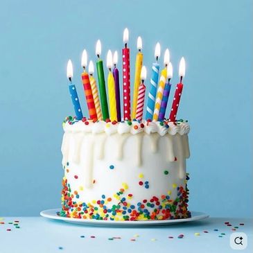 Colorful birthday cake with lit candles and sprinkles.
