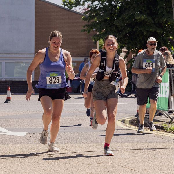 Runners with race numbers 823 and 604 competing in a sunny outdoor race.
