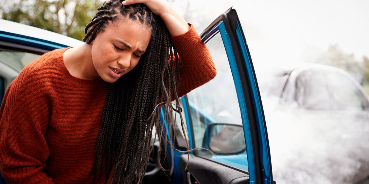 Woman upset by her smoking car with the door open.