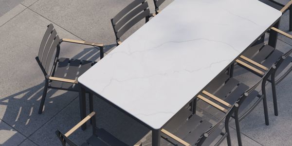 Stone dining table surrounded by teak and aluminum chairs