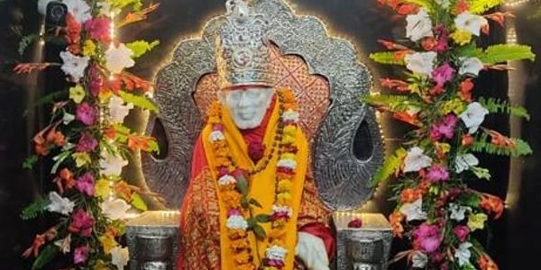 Statue of Sai Baba adorned with garlands and flowers.