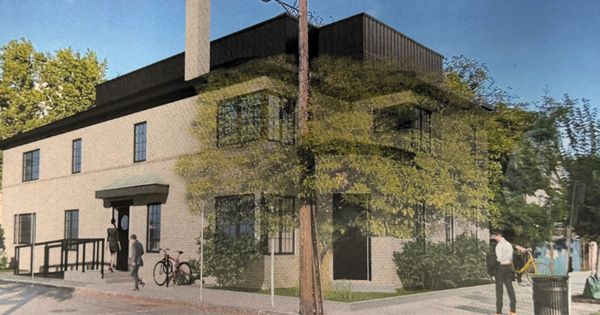 A modern two-story building with people walking nearby and a bicycle parked outside.
