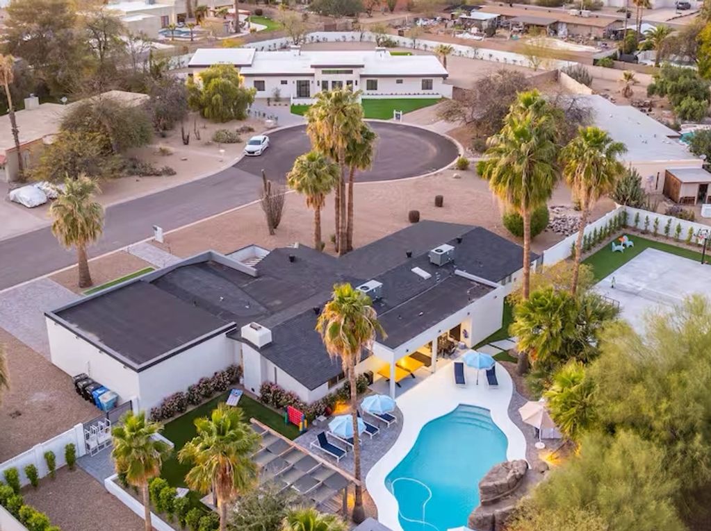 Aerial view of a suburban house with a backyard pool and palm trees.