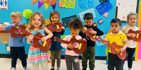 Children playing with toy guitars in a colorful classroom.