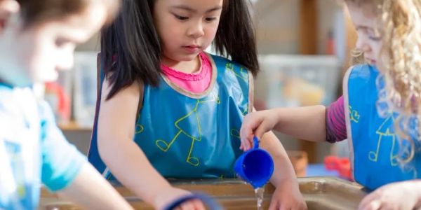Children playing and pouring water in a sensory table.