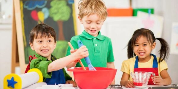 Three children happily cooking together.