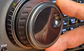 Close-up of a hand adjusting a control knob on a radio device.