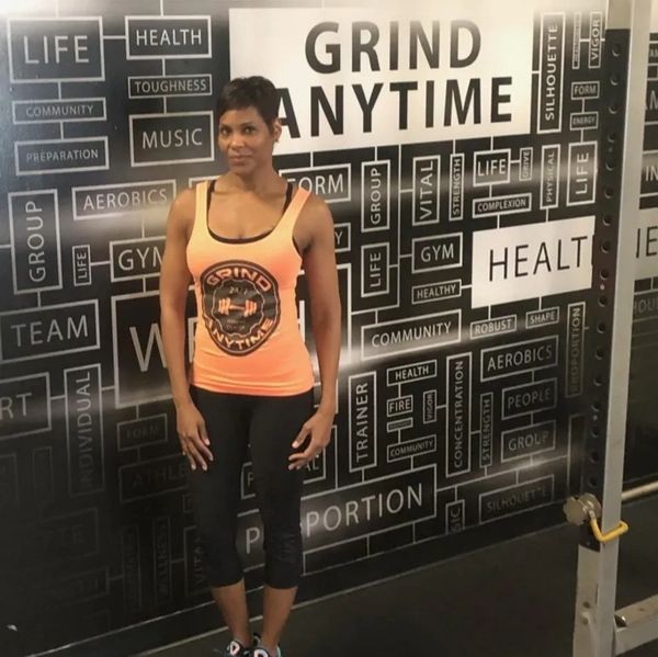 Gerri Bannister standing next to the Grind Anytime motivation wall.