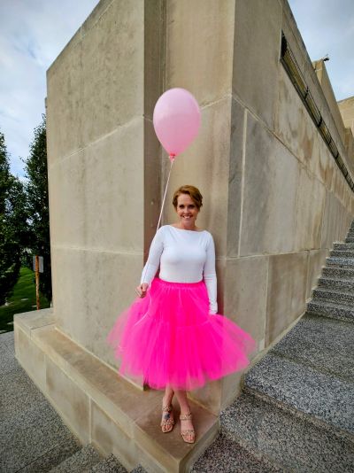Woman in bright pink skirt holding a pink balloon.