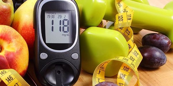 Glucometer, fruits, dumbbells, stethoscope, and measuring tape for healthy lifestyle.