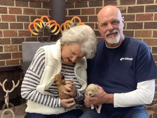 Carolina Country Kennel's owners holding 2 puppies