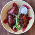 Tender, hickory-smoked chicken ribs displayed on a chili pepper bowl with a simple salad and ranch