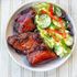 Tender, hickory-smoked chicken ribs displayed on next to a mixed green salad with herbs