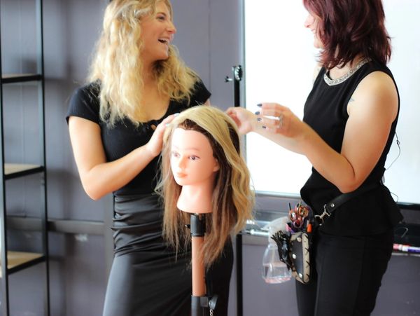 Two people styling a mannequin head