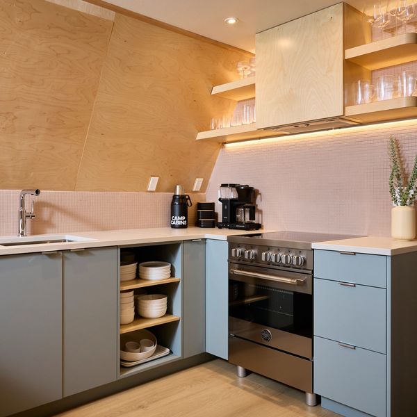 Modern kitchen with blue cabinets, stainless steel stove, and wood accents.