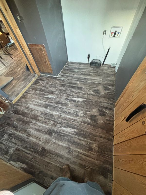 Newly installed dark wood-look flooring in a small laundry area.