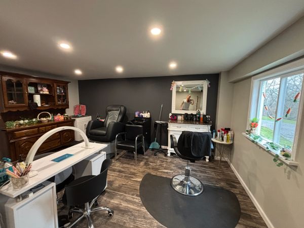 A cozy home salon with chairs, a nail station, and a decorated mirror.