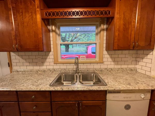 Kitchen sink area with granite countertop and wooden cabinets.