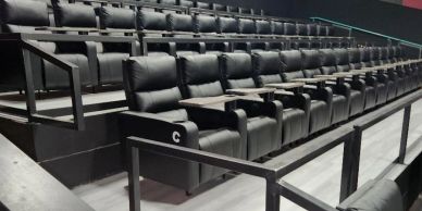 Rows of black leather recliner seats in a theater.