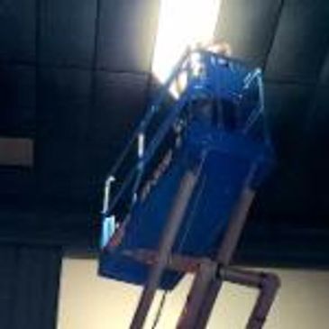 Blue aerial lift platform raised indoors.