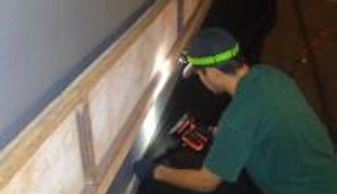 Person using a power tool under a structure.