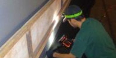 Person using a power tool under a structure.