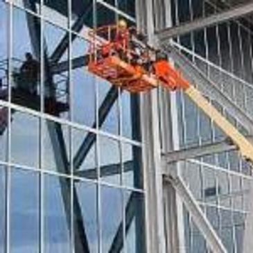 Worker cleaning high windows using a lift.