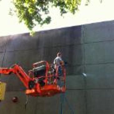 Person on a lift cleaning or painting a large wall.