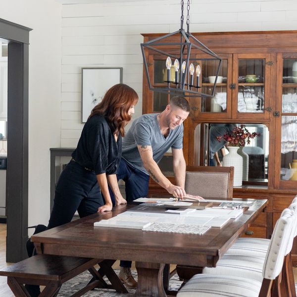 Two people discussing plans over a wooden dining table in a cozy room.