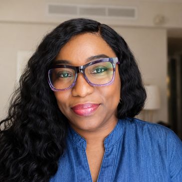 Smiling woman with glasses and wavy hair.
