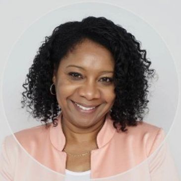 Smiling woman with curly hair in a peach jacket.