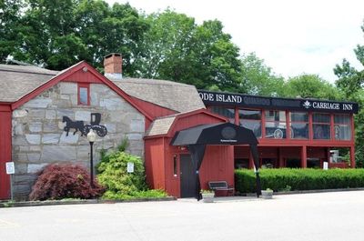 Rhode Island Carriage Inn with stone and red exterior under green trees.