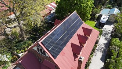 Solar panels installed on a red roof house.