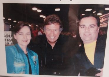Three people posing together indoors, smiling at the camera.