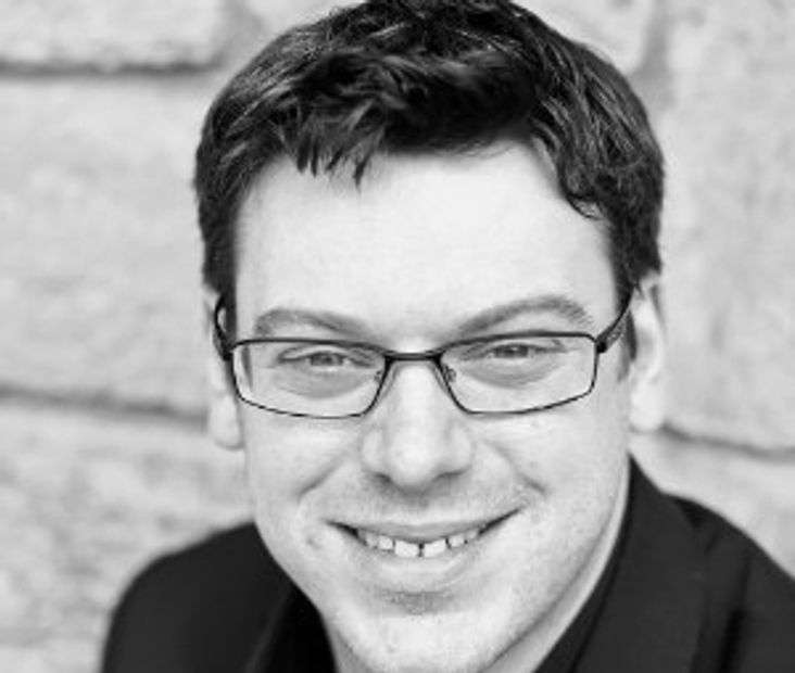 Black and white portrait of a smiling man with glasses.