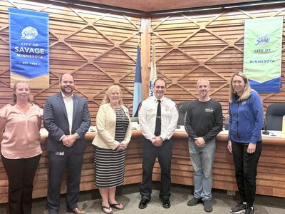Group of six people standing in a city hall meeting room.