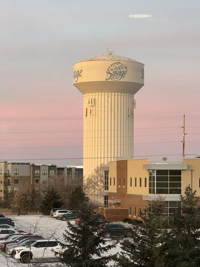 Savage water tower at sunset with snowy ground.
