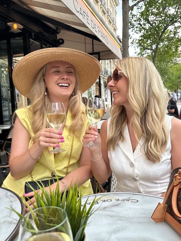 Two women enjoying white wine at an outdoor café in Paris.