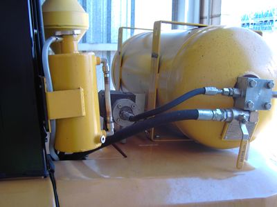 Sistema hidráulico con tanque amarillo y mangueras.