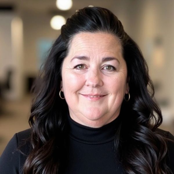Smiling woman with dark curly hair in a black turtleneck.