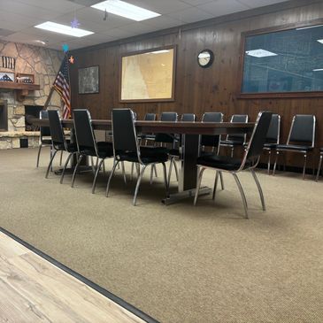A meeting room with a long table and black chairs.