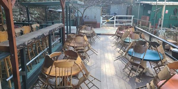 Outdoor patio with wooden tables and chairs stacked upside down.