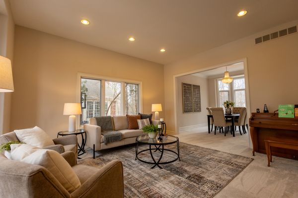 Cozy living room with beige furniture and a connecting dining area with a chandelier.