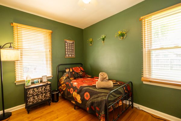 Cozy bedroom with green walls and floral bedding on a single bed.