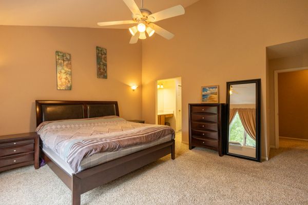 Spacious bedroom with a large bed, wooden furniture, and a ceiling fan.