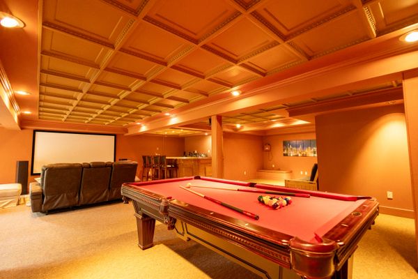 Cozy basement game room with pool table, home theater, and bar area.