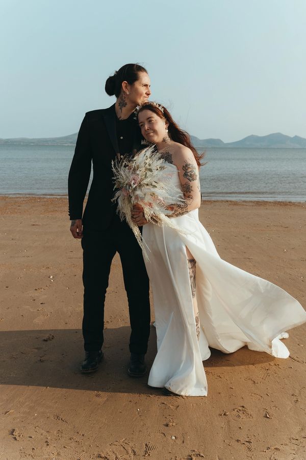 Lesbian LGBTQ+ elopement wedding on beach in Wales - sand, sea, and mountains on the horizon