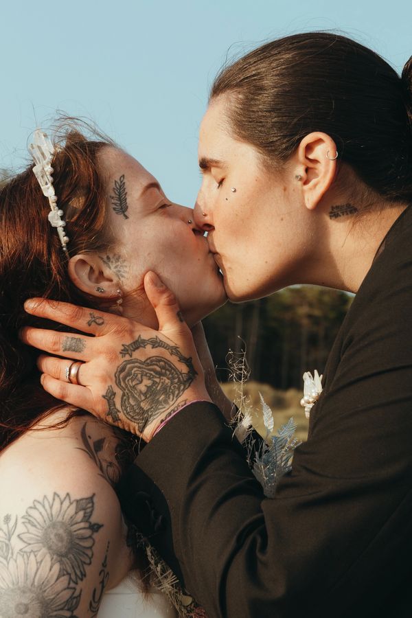 Couple kiss during their elopement wedding ceremony on Anglesey beach - LGBTQ+ lesbian wedding