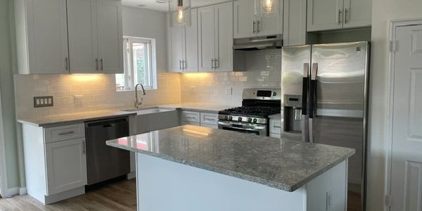 Modern kitchen with white cabinets and stainless steel appliances.