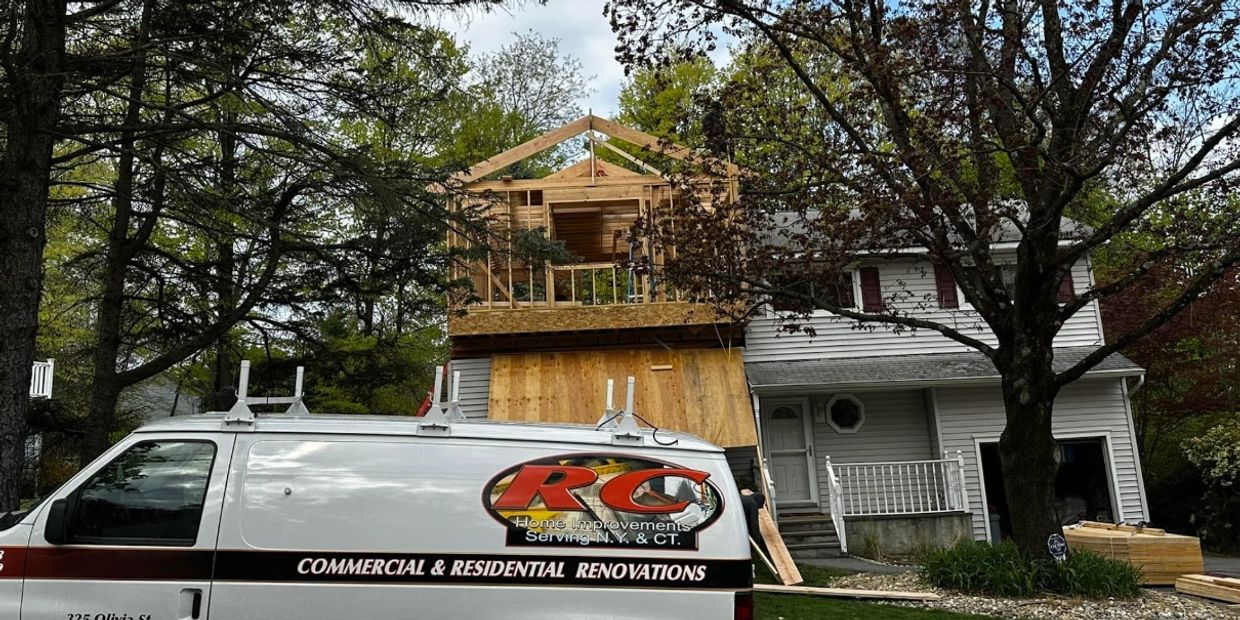Van parked outside house under construction with new wooden frame.